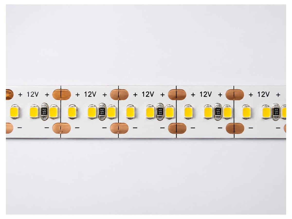 bed-led-strip-component-02 - Custom LED Lighting & OEM LED Modules Supplier Close-up of a white LED strip showing small yellow SMD LEDs and copper power pads labeled +12V across the strip.